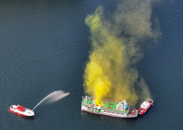 A firefighting service vessel (L) directs water at a pleasure boat on Soyang Lake in Chuncheon, Gangwon Province, northeastern South Korea on October 25, 2023, in a drill that simulates a fire on the boat and an oil leak from it. (Photo by Yonhap/EPA/EFE)
