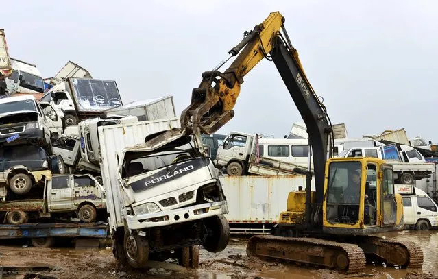 A excavator dismantles a scrapped high-emission car at a dump site of a recycling centre in Yiwu, Zhejiang province April 8, 2015. (Photo by Reuters/China Daily)
