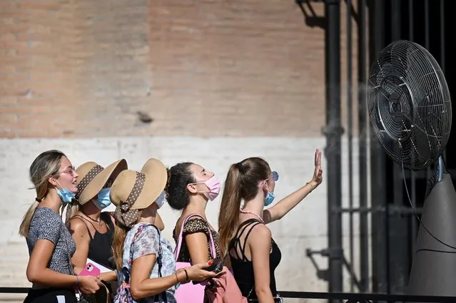A group of woman cool off in front of a cooling fan during a heatwave as they queue at the enterance of the Colosseum in Rome on August 12, 2021. An anticyclone dubbed Lucifer is sweeping across Italy, sending temperatures soaring and causing what is believed to be a new European record of 48.8 degrees Celsius (119.8 Fahrenheit) in Sicily on August 11. (Photo by Alberto Pizzoli/AFP Photo)
