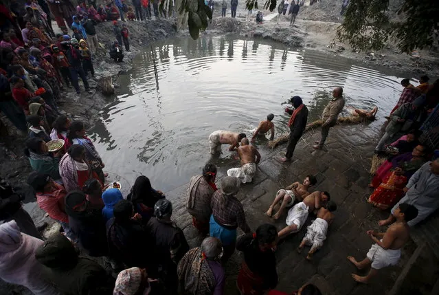 People gather around as devotees offer prayers by rolling near the riverbank of Hanumante River before submerging themselves in the river during a month-long Swasthani Brata Katha festival in Bhaktapur, Nepal, January 27, 2016. (Photo by Navesh Chitrakar/Reuters)
