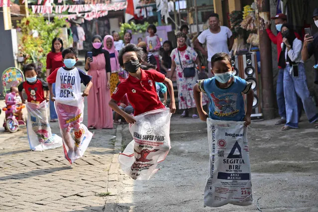 Children, wearing masks to curb the spread of coronavirus outbreak, take part in a sack race competition during an Independence Day celebrations in Jakarta, Indonesia, Tuesday, August 17, 2021. Indonesia is celebrating its 76th anniversary of independence from Dutch colonial rule. (Photo by Tatan Syuflana/AP Photo)