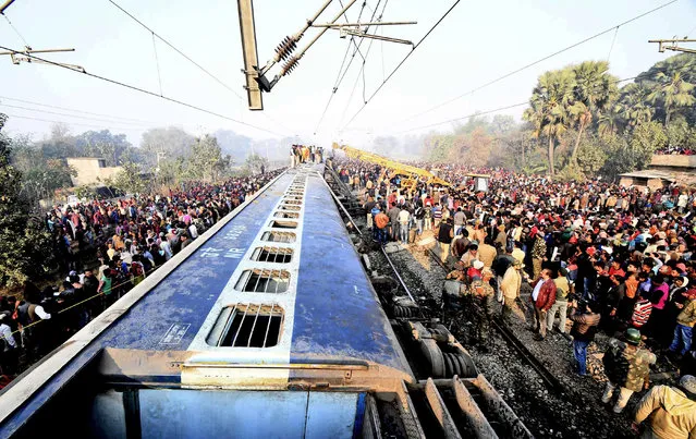 Rescue workers look for survivors as locals stand around the derailed coaches of a train, 30 kilometers (20 miles) north of Patna, the Bihar state capital of India, Sunday, February 3, 2019. Seven coaches of a New Delhi-bound train derailed early Sunday in eastern India. The cause of the accident is being investigated. (Photo by AP Photo/Stringer)