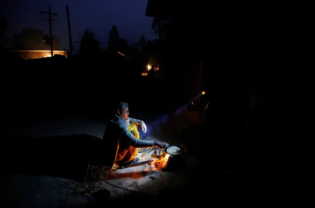 A wife of a snake charmer prepares dinner as her daughter holds a torch in Jogi Dera (snake charmers settlement), in the village of Baghpur, in the central state of Uttar Pradesh, India January 17, 2017. (Photo by Adnan Abidi/Reuters)