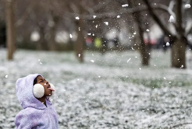 A young girl tries to catch snow on her tongue near the Martin Luther King Jr. Memorial, before the start of a wreath-laying ceremony honoring the legacy of the late civil rights leader in Washington, DC on January 15, 2024. The ceremony is being held to honor the civil rights leader on the anniversary of his birthday. (Photo by Andrew Caballero-Reynolds/AFP Photo)