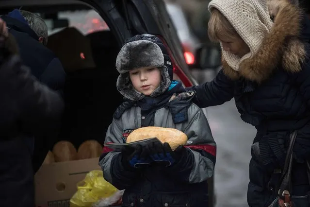 A boy carries a loaf of bread after receiving humanitarian aid in Avdiivka in Avdiivka, Ukraine, Saturday, February 4, 2017. (Photo by Evgeniy Maloletka/AP Photo)