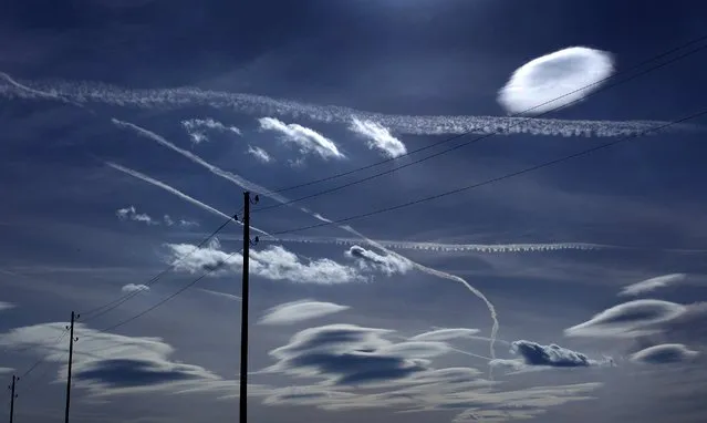 Power supply lines, contrails and clouds paint a graphic design in the sky over Ebersbach, southern Germany, on April 14, 2015. (Photo by Karl-Josef Hildenbrand/AFP Photo/DPA)