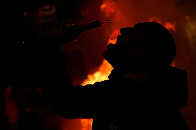 A man drinks wine during the annual “Luminarias” celebration on the eve of Saint Anthony's day, Spain's patron saint of animals, in the village of San Bartolome de Pinares, northwest of Madrid, Spain on January 16, 2024. (Photo by Juan Medina/Reuters)