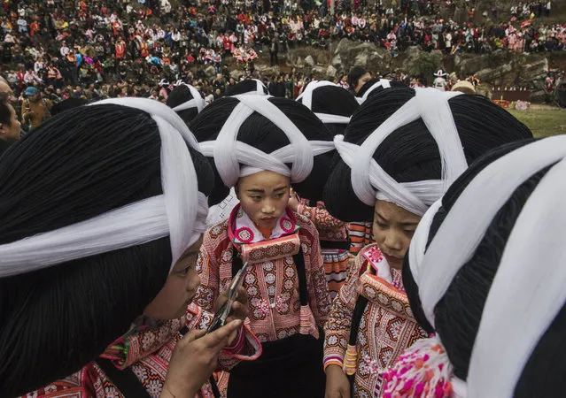 Girls of the Long Horn Miao ethnic minority group wear headdresses as they prepare gather for Tiaohua or Flower Festival as part of the Lunar New Year on February 6, 2017 in Longga village, Guizhou province, southern China. The Long Horn Miao are recognized for their declining practice of wrapping a blend of linen, wool, and the hair of their ancestors around animal horns or a wooden clip to make headdresses. Many young women say they now wear the headdresses only for special occasions and festivals, as the ornaments, which are attached by the horns to their real hair, have proved impractical for modern daily life in a fast changing world. China officially recognizes 56 different ethnic minorities, and statistics show over 7 million Chinese identifying themselves as Miao. But the small Long Horn Miao community counts only around 5000 people living in 12 villages, whose age-old traditions, language, and culture are fading. It is increasingly difficult in a modernizing China, as young people are drawn from remote rural villages to opportunities in bigger cities amongst wide-scale urbanization. Farming and labour remain the mainstays of life for the Long Horn Miao, leaving the area relatively poor in comparison with many parts of China. The government has invested significant amounts into local infrastructure and the tourism industry to try to bolster the local economy. (Photo by Kevin Frayer/Getty Images)