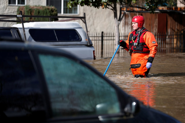 A firefighter with the San Jose Fire Department walks in a flooded neighborhood after heavy rains overflowed nearby Coyote Creek in San Jose, California, U.S., February 21, 2017. (Photo by Stephen Lam/Reuters)