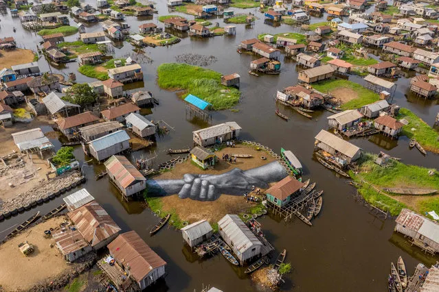 An aerial view of one of the artworks by artist Guillaume Legros, also known as Saype, from his global project, Beyond Walls, in Ganvié, Benin, on March 2, 2021. The “Beyond Walls” project started in Paris in front of the Eiffel Tower and has over several years travelled around the world, from Andorra, Berlin, Geneva, Ouagadougou, Yamoussoukro, Turin, Istanbul and Cape Town before coming to Benin's floating village of Ganvie. (Photo by Yanick Folly/AFP Photo)