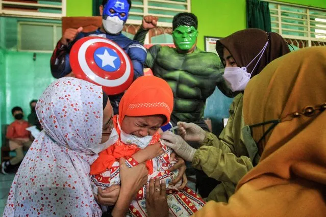 Medical staff dressed in superhero costumes of Captain America and Hulk accompany children age 6 to 11 as they receive the Sinovac COVID-19 coronavirus vaccine at a school in Yogyakarta on January 11, 2022. (Photo by Devi Rahman/AFP Photo)