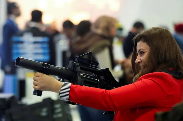 A visitor holds a weapon at the Egyptian stand at Egypt Defence Expo (EDEX), showcasing military systems and hardware, in Cairo, Egypt, November 30, 2021. (Photo by Mohamed Abd El Ghany/Reuters)