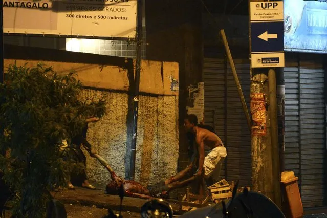 Residents carry a wounded man during a protest against the death of a man in Pavao-Pavaozinho slum, in the Copacabana neighborhood in Rio de Janeiro April 22, 2014. Residents have accused Police Peacekeeping Unit (UPP) officers of causing the death of a dancer, Douglas Rafael da Silva Pereira, 25, who was found dead inside a school at the community, according to local media. (Photo by Lucas Landau/Reuters)