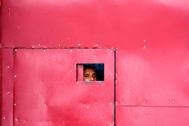 A worker looks through the gate of a closed school in Srinagar on August 19, 2019. Some Kashmir schools re-opened on August 19 but many pupils stayed away, following weekend clashes after India stripped the region of its autonomy and imposed a lockdown two weeks ago. (Photo by Punit Paranjpe/AFP Photo)