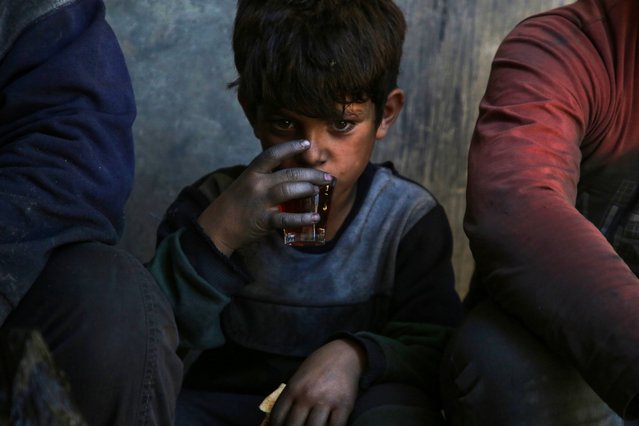 A boy sips a cup of tea during a break from work in an aluminum cookware manufacturing factory in Al-Bab, on the outskirts of Aleppo, on June 2, 2024. (Photo by Aaref Watad/AFP Photo)