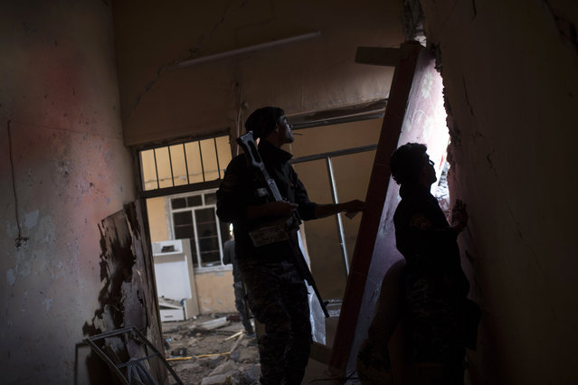 Federal policeman look towards Islamic State positions from a damaged house during fighting at the front line near the old city, on the western side of Mosul, Iraq, Wednesday, March 29, 2017. (Photo by Felipe Dana/AP Photo)