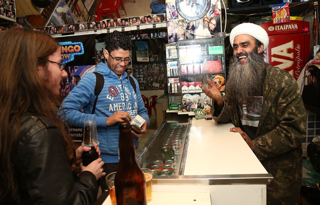 Osama bin Laden lookalike Ceara Francisco Helder Braga Fernandes (R) serves customers in his “Bar do Bin Laden” on April 29, 2014 in Sao Paulo, Brazil. Braga says he was known as the “Beard Man” before 9/11 but became known as a Bin Laden lookalike following the 9/11 attacks. He says he is Christian and continues to play the role to support his business. (Photo by Mario Tama/Getty Images)