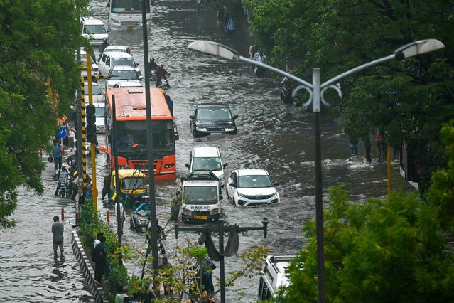 Commuters wade through flooded streets after heavy rains in New Delhi on June 28, 2024. (Photo by Arun Sankar/AFP Photo)