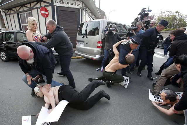 Femen activists with masks, including one wearing a mask of Marine Le Pen, top left, are detained as they demonstrate in Henin-Beaumont, northern France, where far-right leader and presidential candidate Le Pen will vote, during the first round of the French presidential election, Sunday, April 23, 2017. (Photo by Michel Spingler/AP Photo)