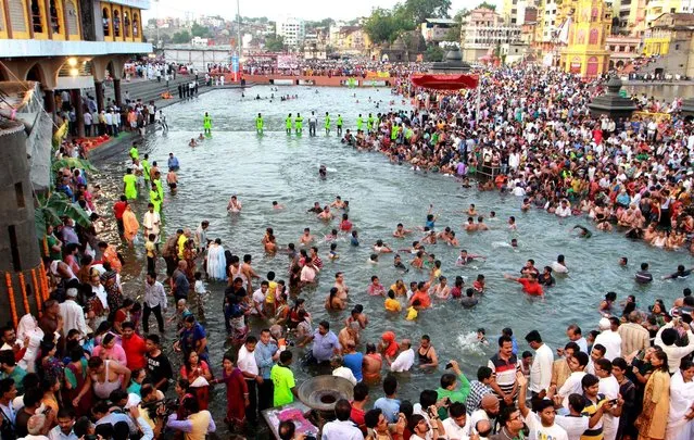 Hindu Indian pilgrims take a dip at the start of the holy Kumbh Mela in Nashik on July 14, 2015. India's mass Hindu pilgrimage, the Kumbh Mela, officially started on July 14 with a low-key flag-raising ceremony in Nashik in western Maharashtra state. While the hoisting marked the official opening of the 2015 Kumbh Mela, only a few hundred pilgrims attended the ceremony and mass crowds are not expected to gather until the first main bathing day on August 29. (Photo by AFP Photo)
