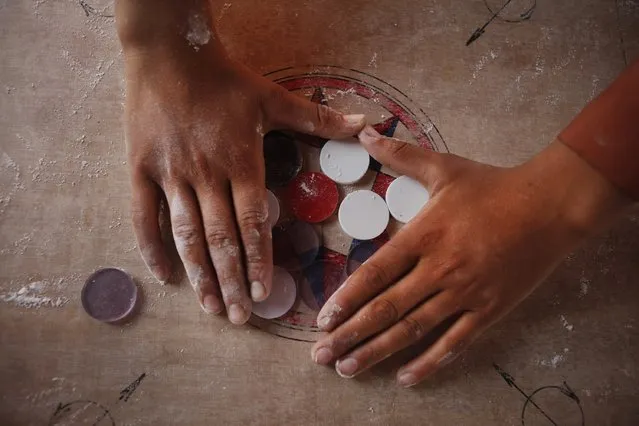 In this Wednesday, July 8, 2015 photo, a boy arranges disks for a game of carrom during break time at a school in Kathmandu, Nepal. (Photo by Niranjan Shrestha/AP Photo)