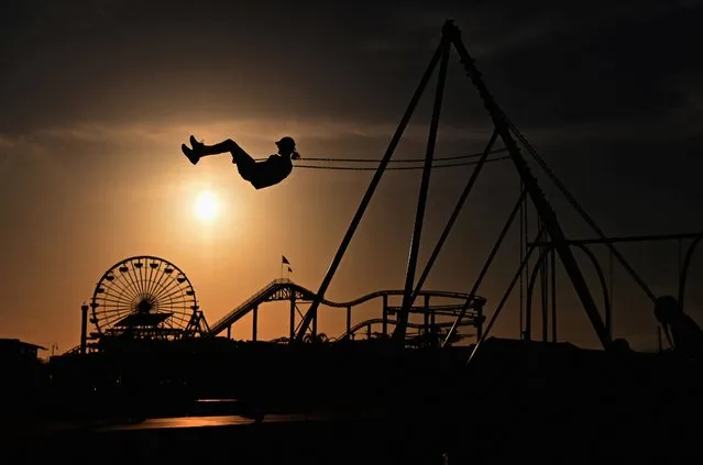A person rides a swing at Santa Monica Beach, California on March 30, 2022. (Photo by Angela Weiss/AFP Photo)