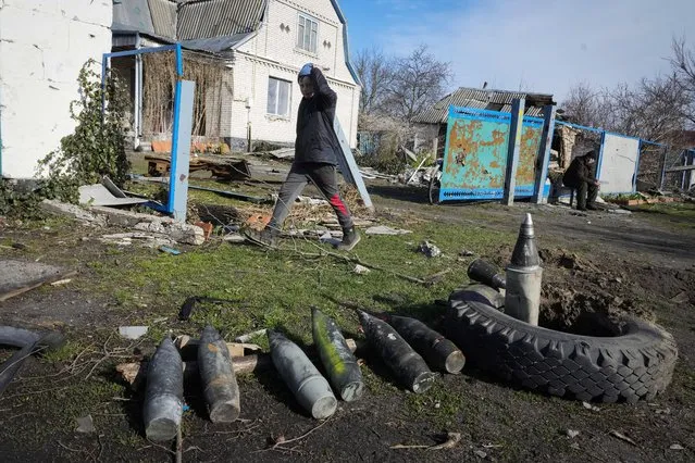 A boy walks by unexploded Russian shells in the village of Andriyivka close to Kyiv, Ukraine, Monday, April 11, 2022. (Photo by Efrem Lukatsky/AP Photo)