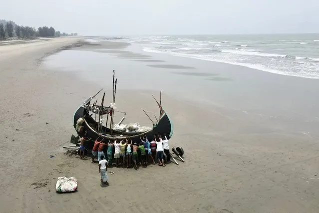 Fishermen try to lift a stranded boat after fishing from the Bay of Bengal in Teknaf on March 28, 2022. (Photo by Munir Uz Zaman/AFP Photo)