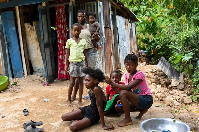 Madelaine Pierre Rose who was affected by the recent earthquake poses for a portrait with her daughters outside of their damaged home on August 21, 2021 in Maniche, Haiti. The magnitude 7.2 earthquake last week destroyed many buildings and homes in the southwest area of Haiti killing over 2,000 people and leaving thousands homeless and searching for food. (Photo by Joshua Lott/The Washington Post)