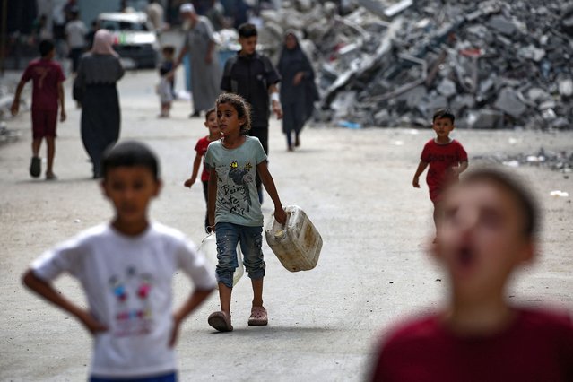 A Palestinian child walks toward a water distribution point in the Bureij refugee camp in central Gaza Strip on August 25, 2024, amid the ongoing conflict between Israel and the Palestinian Hamas militant group. (Photo by Eyad Baba/AFP Photo)