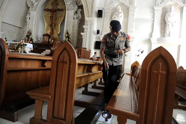 Police officer checks during a security sweep ahead of the Christmas Eve mass at the Holy Spirit Catholic Church of Denpasar Cathedral, Bali, Indonesia on December 24, 2019. (Photo by Fikri Yusuf/Antara Foto via Reuters)