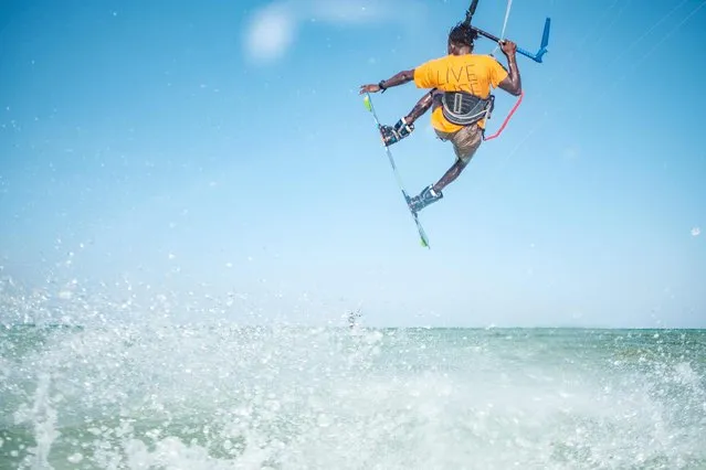 Rama, a kite surfing teacher, surfs in Paje beach, Zanzibar, on January 12, 2022. During high season, Zanzibars beaches attract thousands of people for kite surfing, economically benefitting local businesses. (Photo by Sumy Sadurni/AFP Photo)