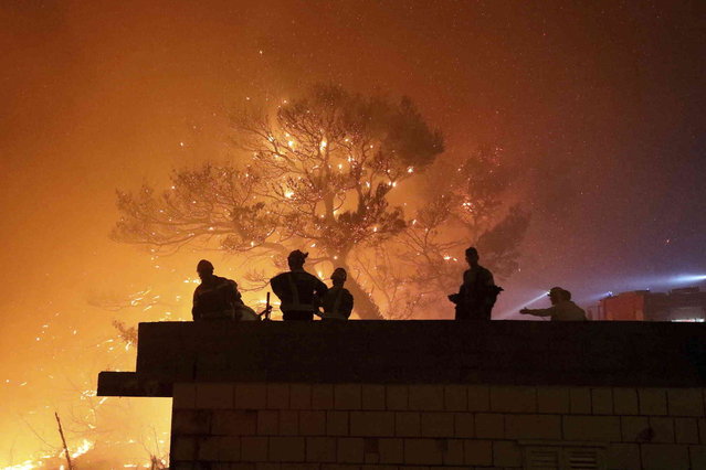 Firefighters gather near the wildfire in Tucepi, Croatia, late Tuesday, July 30, 2024. Croatia's Firefireghters' Association described the last 24 hours as “the most demanding so far”, with more than 100 interventions over 1,000 firefighters and 20 firefighting planes. (Photo by Ivo Ravlic/Cropix via AP Photo)