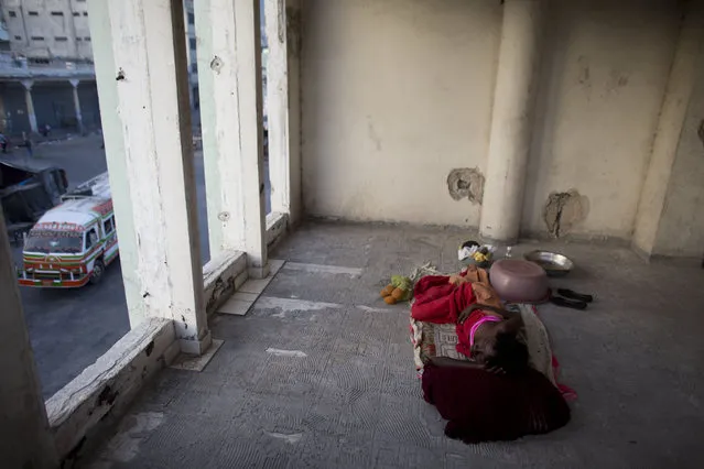 In this June 29, 2015 photo, Zarmor Sendi sleeps in an open room inside an abandoned, earthquake damaged government office building where she's living in Port-au-Prince, Haiti. During the day, Sendi inhabits one of the building's former bathrooms, too small to lie down in, and protected only by a thin curtain. Although the building's residents all know each other, there is no way to secure the site, leaving children and single women like Sendi particularly vulnerable. (Photo by Rebecca Blackwell/AP Photo)