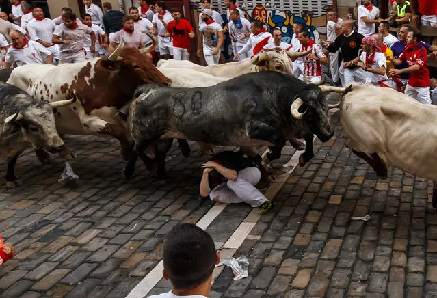 Cebada Gago's fighting bulls jump over a runner on the first day of the San Fermin bull run festival in Pamplona, northern Spain on July 8, 2017. Each day at 8:00 am hundreds of people race with six bulls, charging along a winding, 848.6-metre (more than half a mile) course through narrow streets to the city's bull ring, where the animals are killed in a bullfight or corrida, during this festival, immortalised in Ernest Hemingway's 1926 novel “The Sun Also Rises” and dating back to medieval times and also featuring religious processions, folk dancing, concerts and round-the-clock drinking. (Photo by Cesar Manso/AFP Photo)