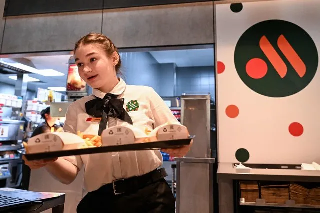 An employee holds a food order on a tray in the Russian version of a former McDonald's restaurant after the opening ceremony in Moscow on June 12, 2022. Former McDonald's restaurants in Russia have been renamed “Vkusno i tochka” (“Delicious. Full Stop”), the new owner said ahead of their grand re-opening . (Photo by Kirill Kudryavtsev/AFP Photo)
