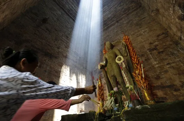Cambodian tourists burn incense next to a statue at the World Heritage site Sambor Prei Kuk temple, in Kampong Thom province, Cambodia, 06 August 2017. According to local media reports, Cambodia received 2,662,679 International visitors during a six month period in 2017, with an increase of 12.8 percent to compare with the same period of 2016. (Photo by Mak Remissa/EPA/EFE)