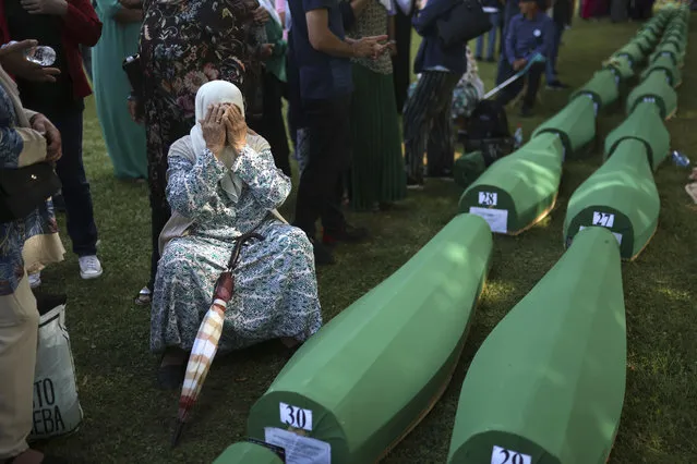 A Bosnian muslim woman, Bahta Aljic mourns next to the coffin containing remains of her husband who is among 50 newly identified victims of Srebrenica Genocide in Potocari, Monday, July 11, 2022. Thousands converge on the eastern Bosnian town of Srebrenica to commemorate the 27th anniversary on Monday of Europe's only acknowledged genocide since World War II. (Photo by Armin Durgut/AP Photo)