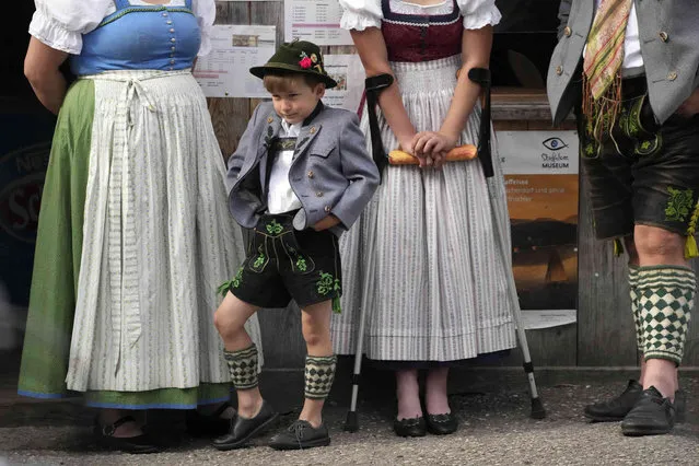 A young boy wearing traditional clothes awaits the start of a Corpus Christi procession at lake Staffelsee in Seehausen near Murnau, Germany, Thursday, June 16, 2022. (Photo by Matthias Schrader/AP Photo)