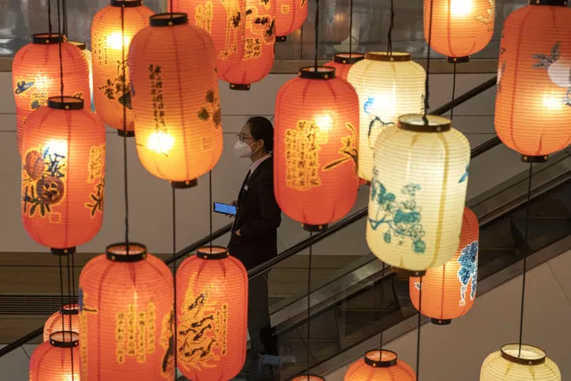 An office worker wearing a mask against coronavirus moves past lantern decorations in a mall and office building in Beijing on Thursday, March 19, 2020. China has only just begun loosening draconian travel restrictions within the country, but has stepped-up 14-day quarantine regulations on those arriving in Beijing, Shanghai and elsewhere from overseas, amid expectations of a new influx of students and others returning home. (Photo by Ng Han Guan/AP Photo)