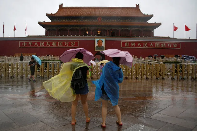Tourists hold umbrellas as they stand in front of the Tiananmen Gate and a giant portrait of Chinese late Chairman Mao Zedong on a day of heavy rain in Beijing, China, July 20, 2016. (Photo by Thomas Peter/Reuters)