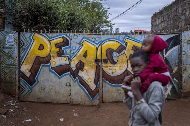 A boy carries a baby past a gate on which is written “Peace” in the Kibera neighborhood of Nairobi, Kenya Sunday, August 14, 2022. (Photo by Ben Curtis/AP Photo)