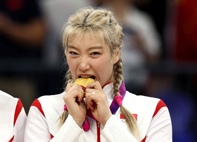 Gold medallist Li Meng of Team China bites her medal on the podium during the women's-basketball medal ceremony at the Asian Games in Hangzhou, China, on October 5, 2023. (Photo by Marko Djurica/Reuters)