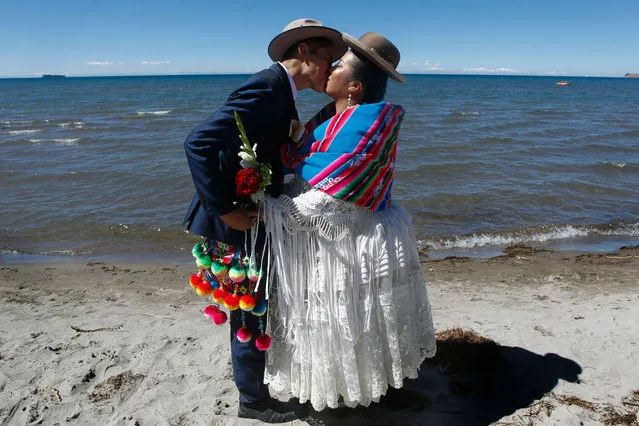 Ecuadorian Bryan Rosel and his wife Magdalena Llanque -who met more than a year ago through social media- kiss after getting married during a mass wedding ceremony where fifty couples got married at the shore of lake Titicaca in the Aymara district of Acora in Puno, Peru, on August 20, 2022. The public act was organized by the local municipality and held applying a mixture of modern and ancestral Andean customs, including the presence of their native Yatiri (Shaman) who made a payment to the Pachamama (Mother Earth) to wish good to the couples. (Photo by Carlos Mamani/AFP Photo)