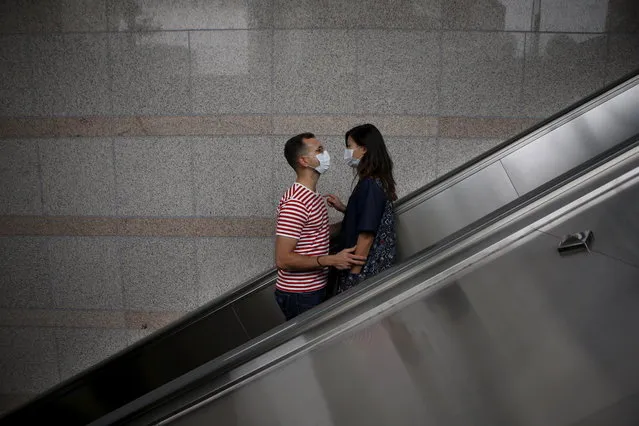 A couple wearing masks to prevent contracting MERS looks at each other as they ride on an escalator in Seoul, South Korea, June 11, 2015. (Photo by Kim Hong-Ji/Reuters)