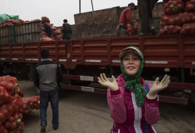 A Chinese vegetable vendor gestures as she wears rubber gloves while unloadeing a truck of onions at a local market on September 26, 2014 in Beijing, China. (Photo by Kevin Frayer/Getty Images)