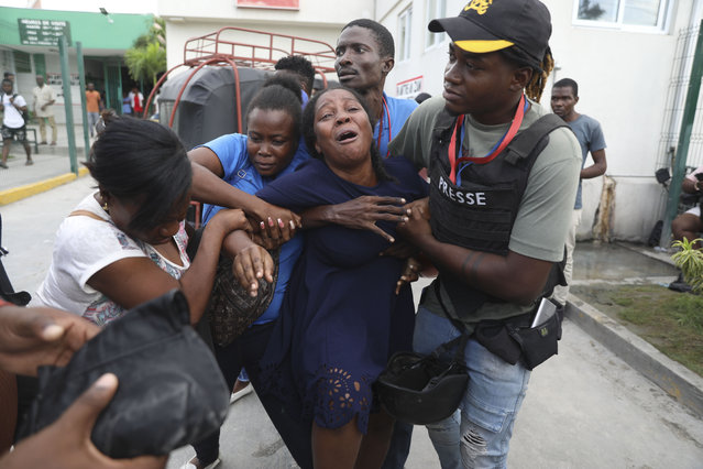 The wife of a journalist, who was shot during an armed gang attack on the General Hospital, cries as an ambulance arrives with his body, at a different hospital in Port-au-Prince, Haiti, Tuesday, December 24, 2024. (Photo by Odelyn Joseph/AP Photo)