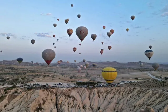 This aerial view shows hot air balloons launching in Goreme Historical National Park, east of Nevesehir (Neapolis) in the province of the same name in central Turkey's historical Cappadocia (Kapadokya) region on August 24, 2022. (Photo by Omar Haj Kadour/AFP Photo)