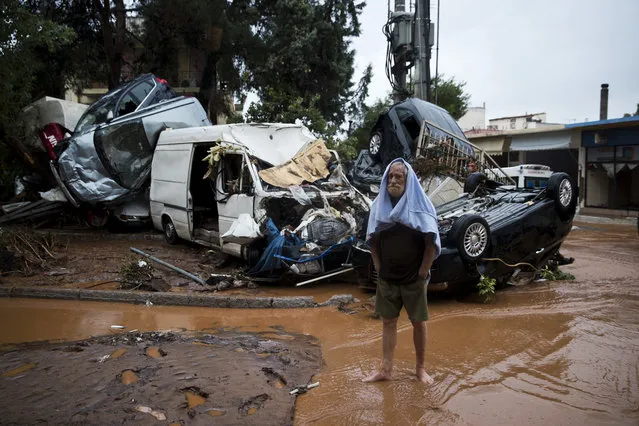 A barefoot man stands in front of a pile of vehicles in the municipality of Madra western Athens, on Wednesday, November 15, 2017. Flash floods in the Greek capital's western outskirts Wednesday turned roads into raging torrents of mud and debris, killing at least nine people, inundating homes and businesses and knocking out a section of a highway. (Photo by Petros Giannakouris/AP Photo)