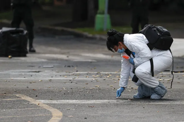 A forensic investigator collects cartridges at the scene where the Mexican capital's police chief was attacked by gunmen in Mexico City, Friday, June 26, 2020. Heavily armed gunmen attacked and wounded Omar García Harfuch in an operation that left several dead. (Photo by Rebecca Blackwell/AP Photo)